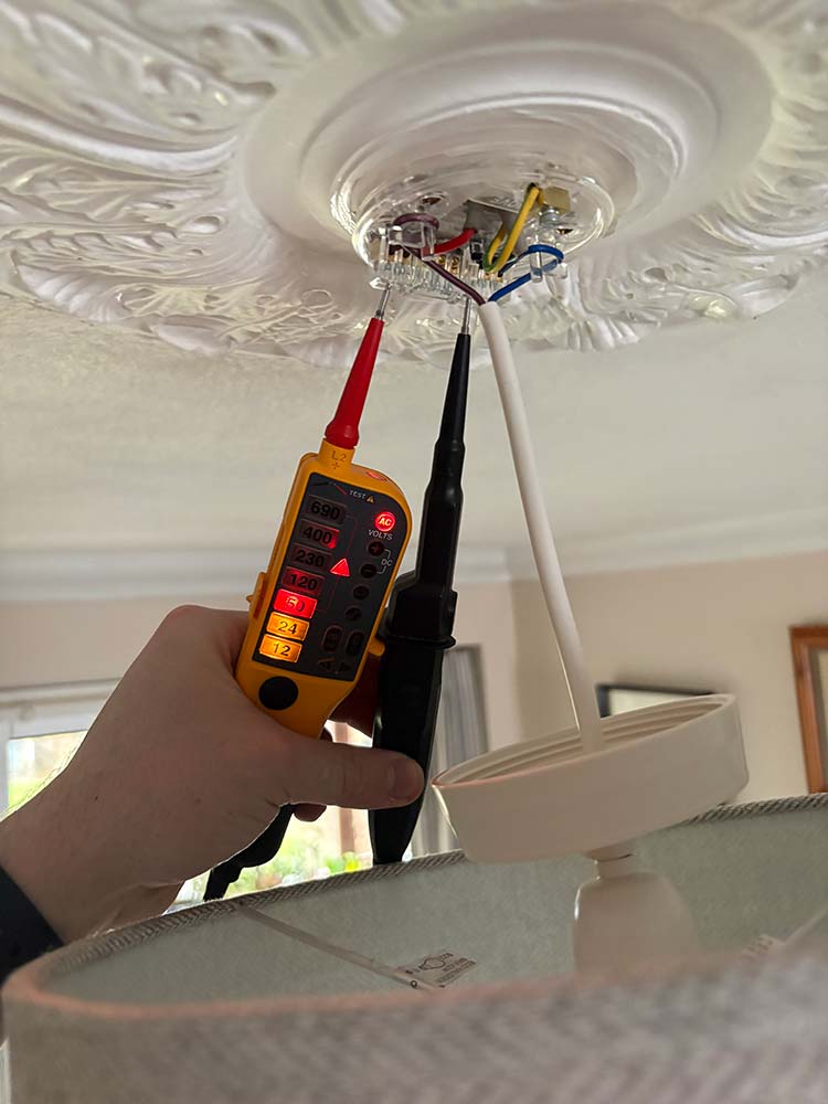 Electrician testing a ceiling light circuit during electrical fault finding