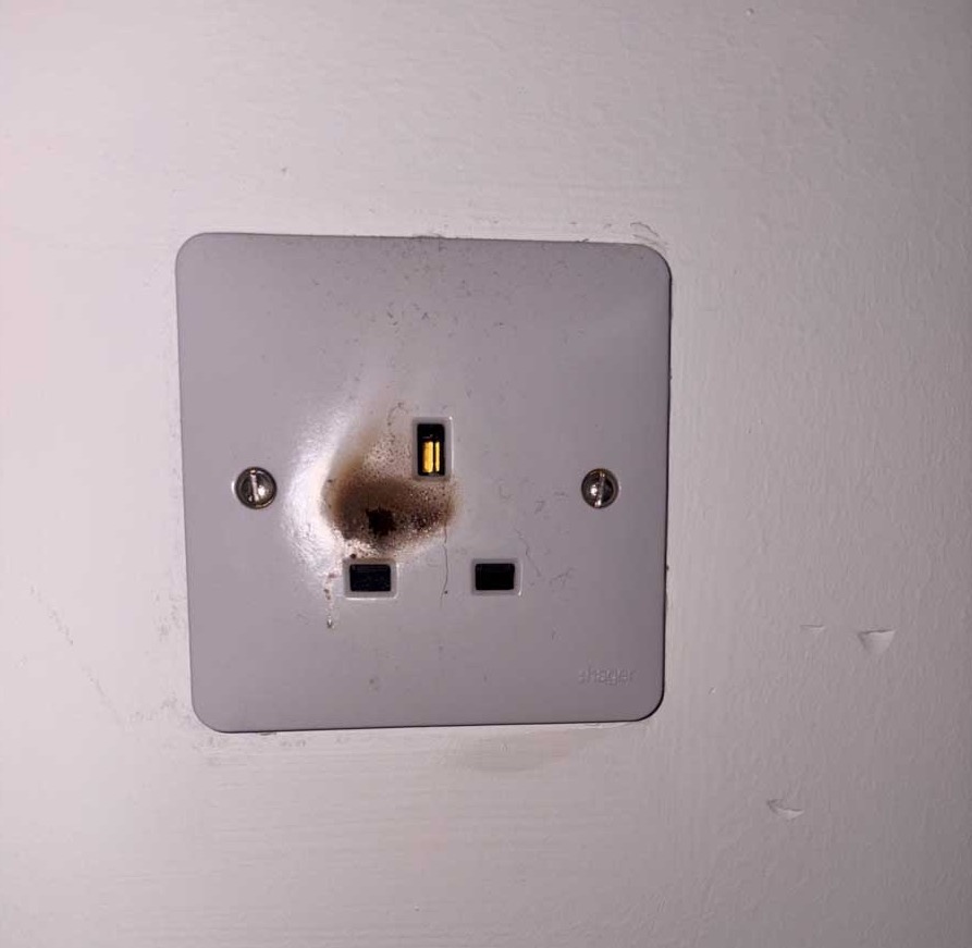 Burnt electrical wall socket showing dangerous overheating and fire damage